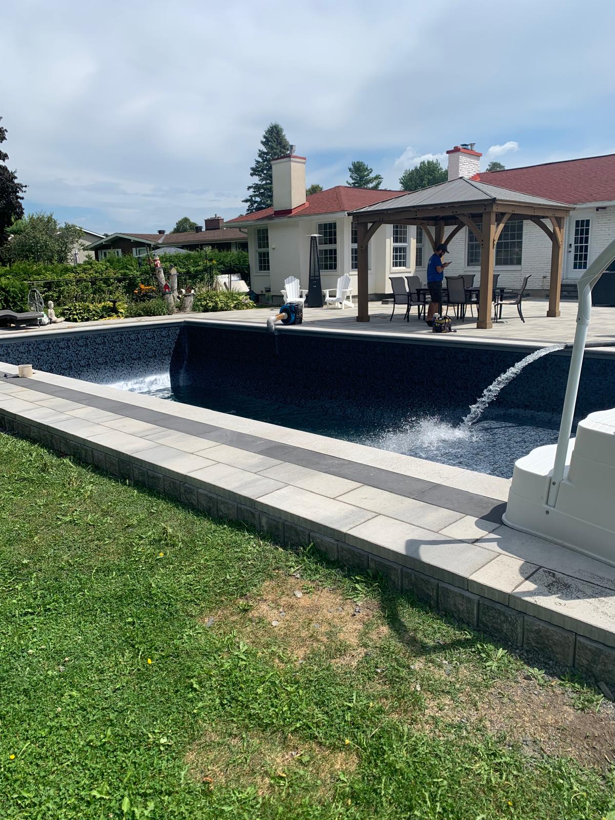 Poolside interlocking patio with pergola and water feature