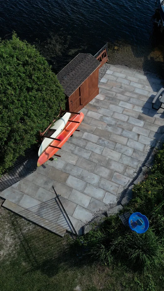 Waterfront interlocking patio with kayaks and garden shed